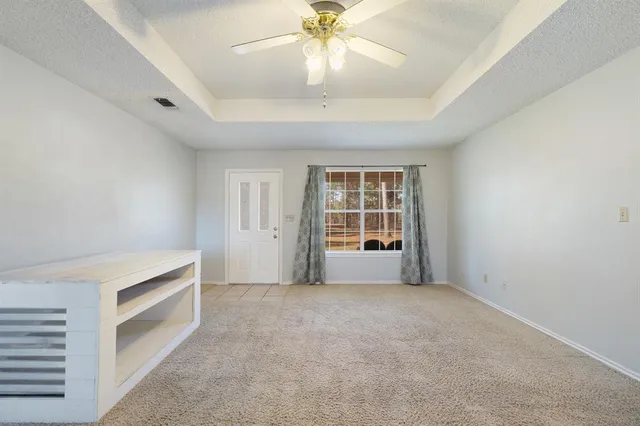 an empty room with windows and ceiling fan