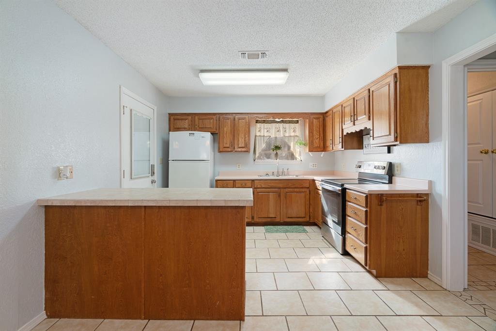 201 County Road Powderly, TX 75473 - Photo 7 of 26 a kitchen with stainless steel appliances granite countertop a sink counter space and a refrigerator