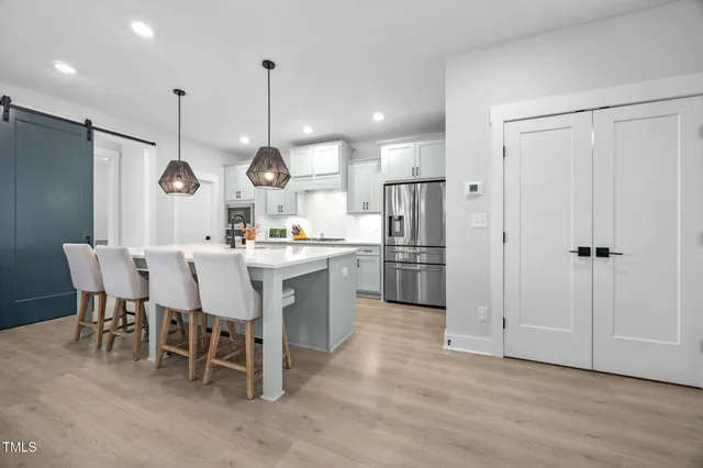 a kitchen with stainless steel appliances granite countertop a sink a stove a refrigerator and island with wooden floor