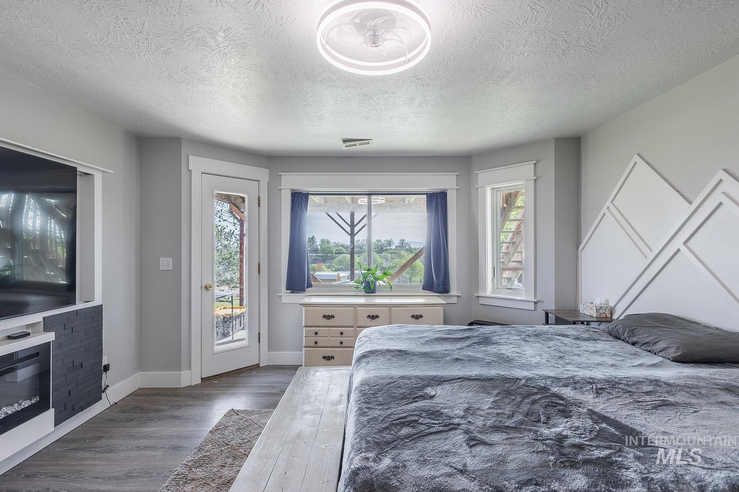 3950 Cassia Road New Plymouth, ID 83655 - Photo 15 of 26 Bedroom featuring wood finished floors, access to outside, and a textured ceiling