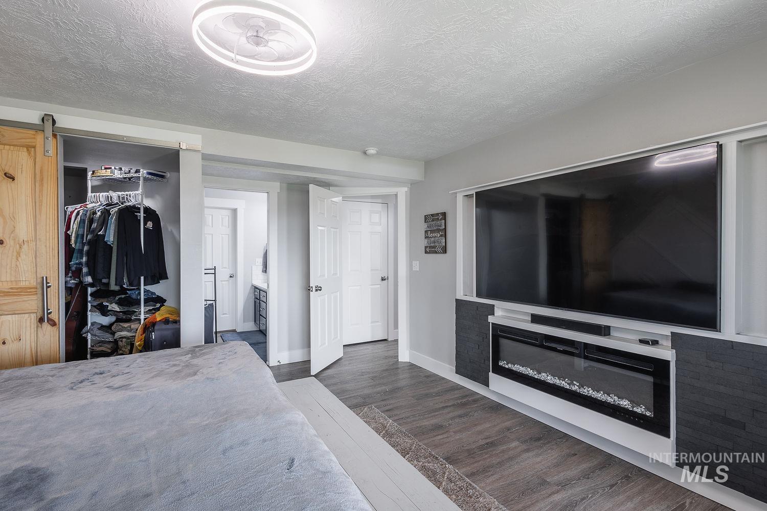 3950 Cassia Road New Plymouth, ID 83655 - Photo 16 of 26 Bedroom featuring dark wood-type flooring, connected bathroom, a textured ceiling, a barn door, and a closet