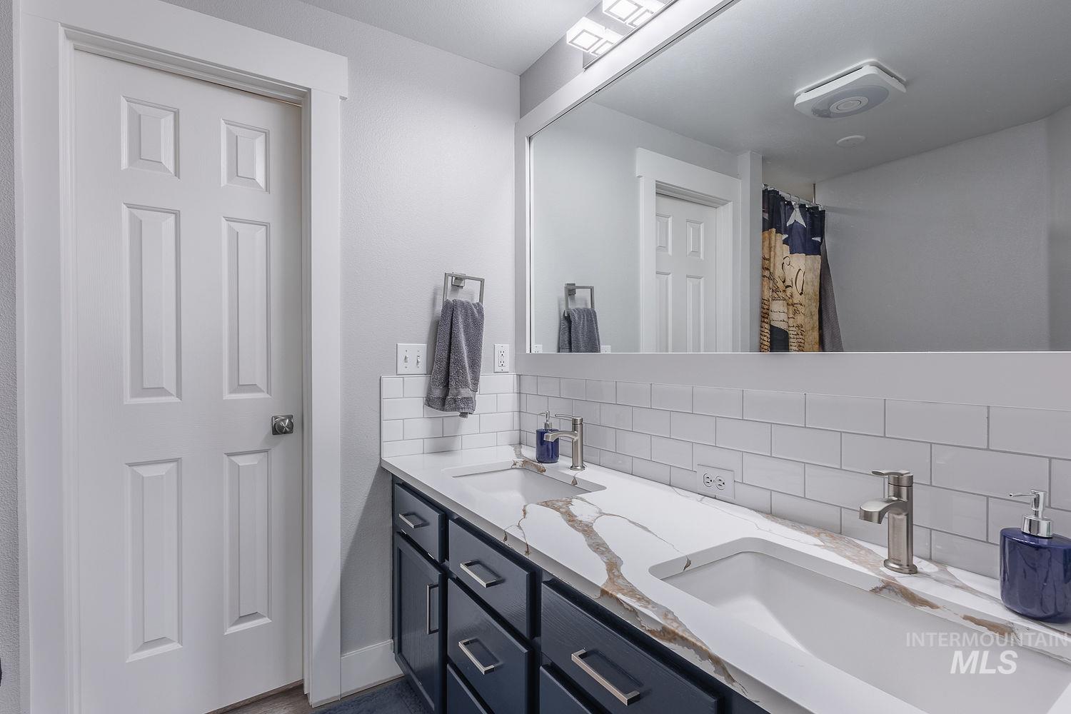 3950 Cassia Road New Plymouth, ID 83655 - Photo 17 of 26 Bathroom with double vanity, backsplash, and a shower with shower curtain