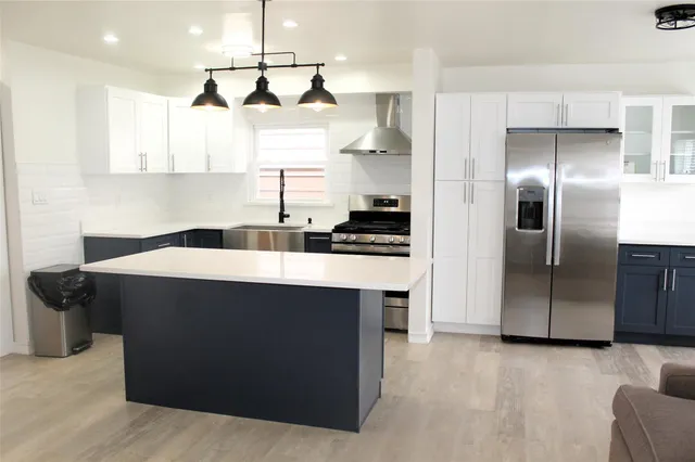 a kitchen with stainless steel appliances kitchen island granite countertop a refrigerator a sink and a stove