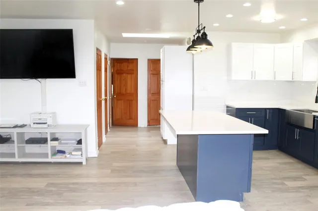 a kitchen with stainless steel appliances kitchen island granite countertop a refrigerator a stove and a sink with wooden floor