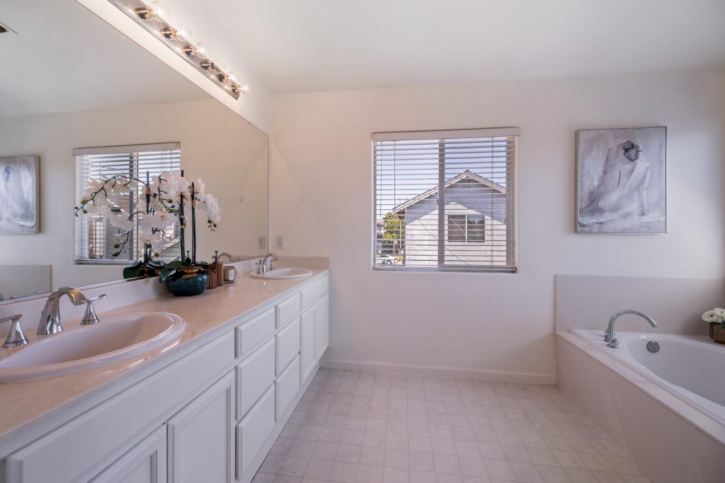 8981 Del Rio Circle Gilroy, CA 95020 - Photo 17 of 35 a bathroom with a double vanity sink a mirror and a bathtub