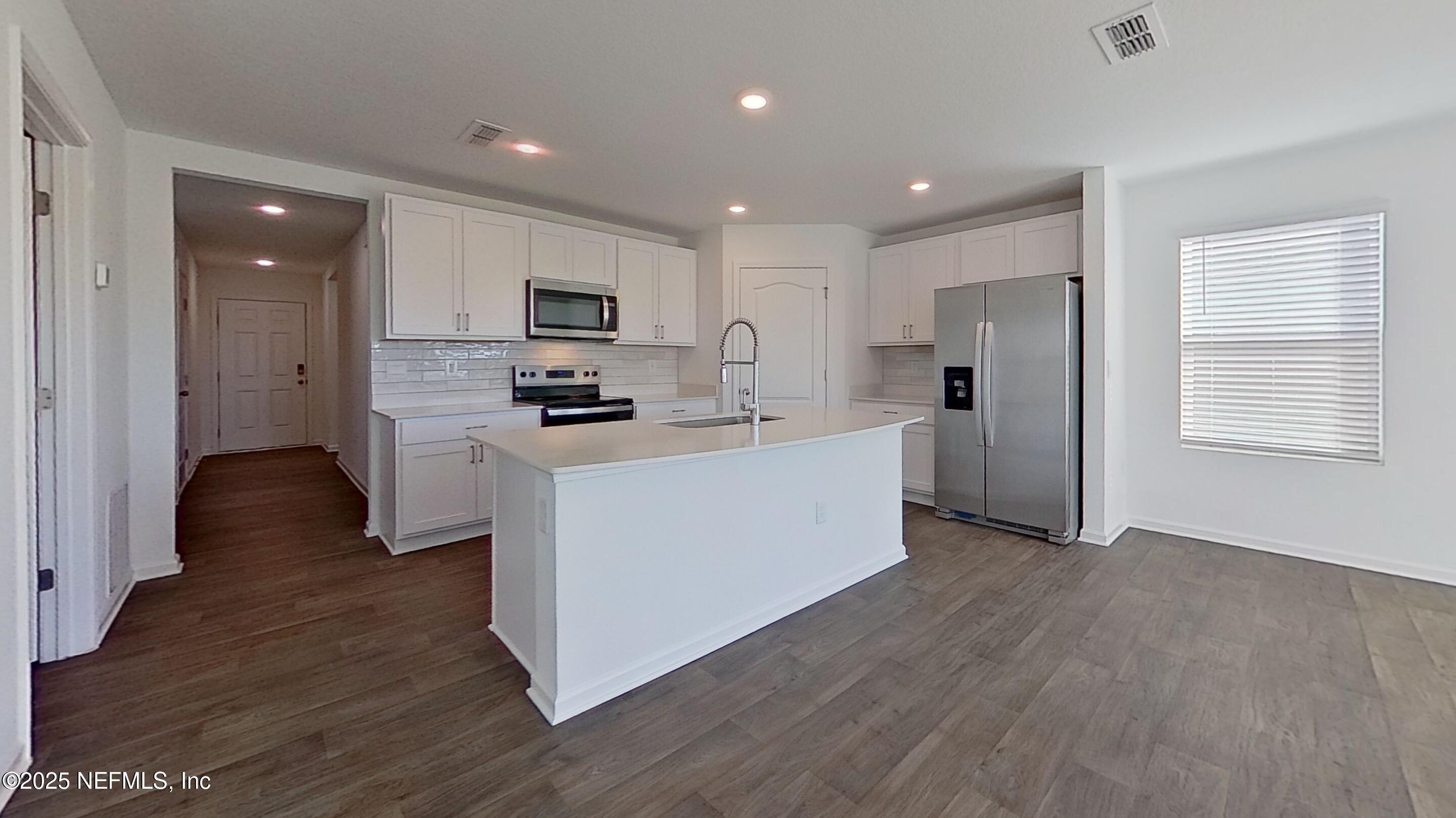 12452 Rubber Fig Terrace Jacksonville, FL 32218 - Photo 8 of 25 a kitchen with stainless steel appliances granite countertop a stove top oven a sink a refrigerator and white cabinets with wooden floor