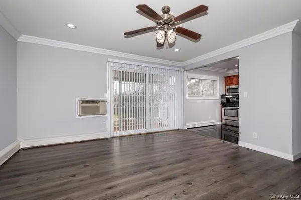 a view of an empty room with a window and wooden floor