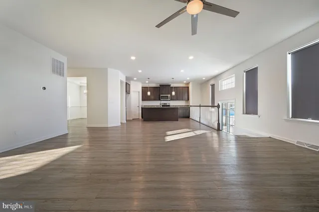 a view of a living room a kitchen with a refrigerator and a floor to ceiling window