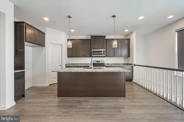 a view wooden kitchen with granite countertop stainless steel appliances cabinets a sink and a wooden floor