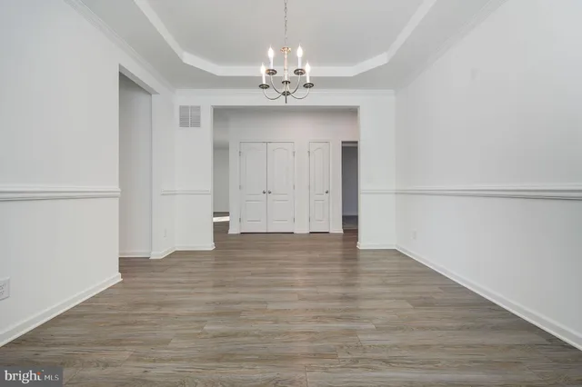 a view of an empty room with wooden floor and chandelier