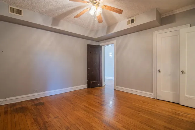 a view of an empty room with a window and wooden floor