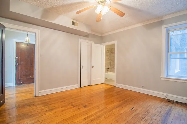 an empty room with wooden floor and windows
