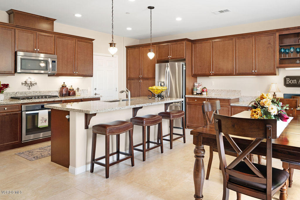 4805 Edenbridge Road Moorpark, CA 93021 - Photo 8 of 44 a kitchen with stainless steel appliances granite countertop a table chairs sink refrigerator and microwave