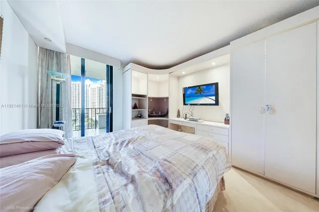 a bedroom with a large bed and a flat tv screen