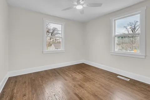 a view of an empty room with wooden floor and window