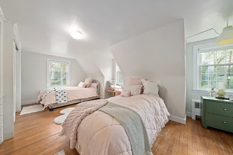 a bedroom with two beds and wooden floor