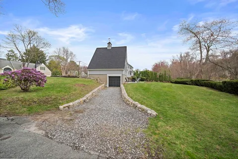 a view of a house next to a big yard with large trees