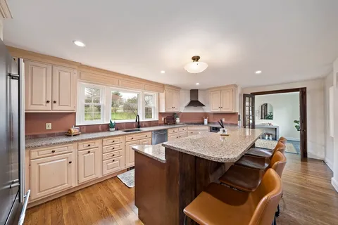 a large kitchen with a large counter top space a sink stainless steel appliances and cabinets