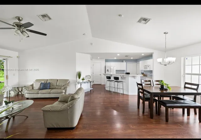 a living room with furniture kitchen view and a wooden floor