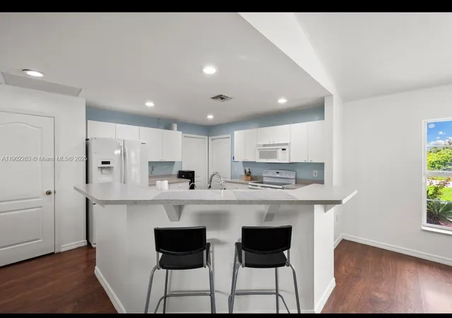 a large white kitchen with stainless steel appliances granite countertop a stove and a refrigerator