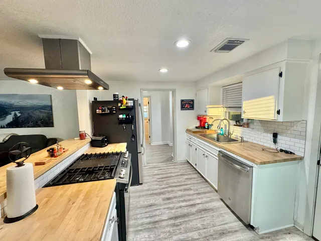 a large white kitchen with stainless steel appliances kitchen island granite countertop a sink and cabinets