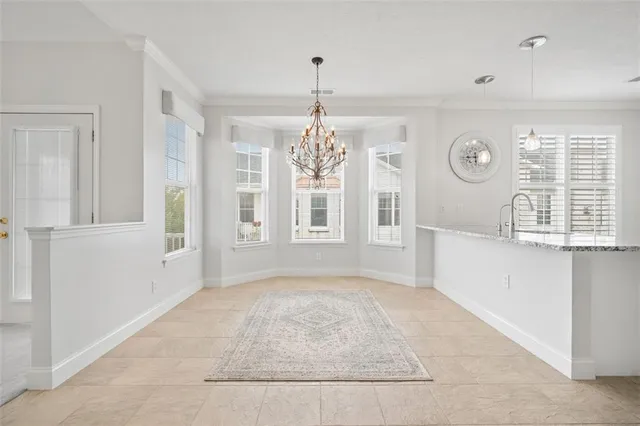 a view of an empty room with window and chandelier fan
