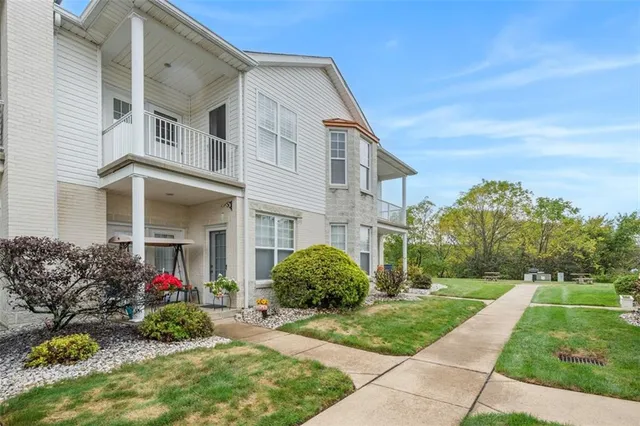 a view of a house with a small yard and a large tree