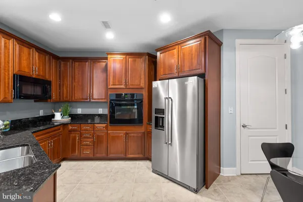 a kitchen with stainless steel appliances granite countertop a refrigerator a sink dishwasher a stove a kitchen island and cabinets