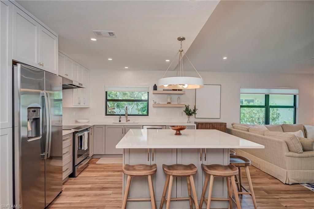 577 98th Avenue North Naples, FL 34108 - Photo 33 of 33 a kitchen with stainless steel appliances a dining table chairs stove refrigerator and microwave