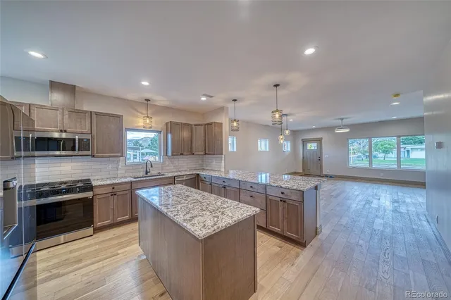a kitchen with kitchen island granite countertop a sink stove and refrigerator