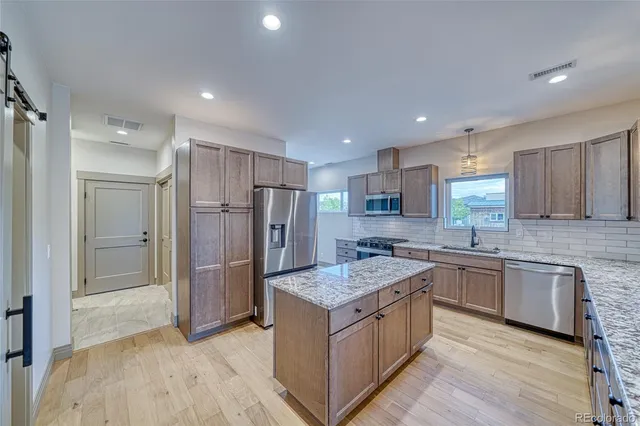 a kitchen with granite countertop a sink stainless steel appliances and cabinets