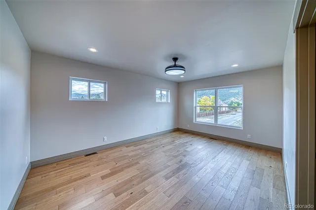 an empty room with wooden floor and windows