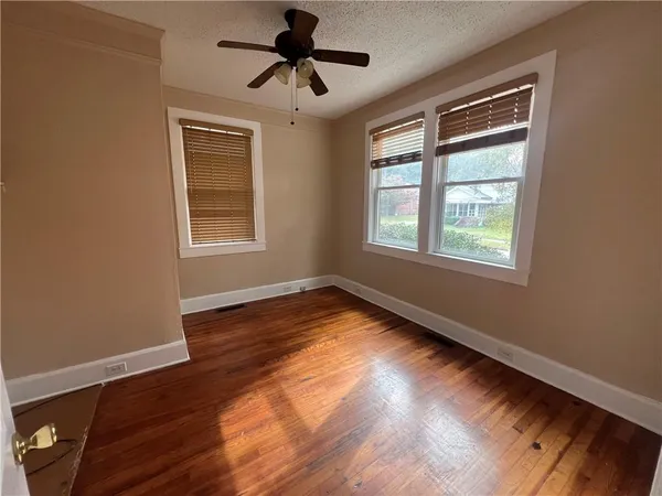 a view of empty room with wooden floor and fan