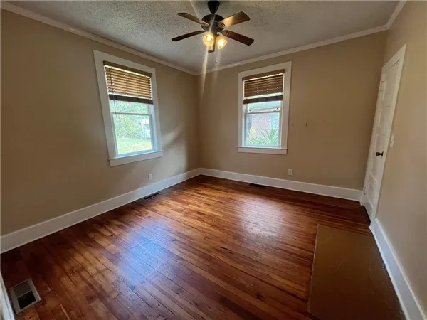 a view of empty room with wooden floor and fan