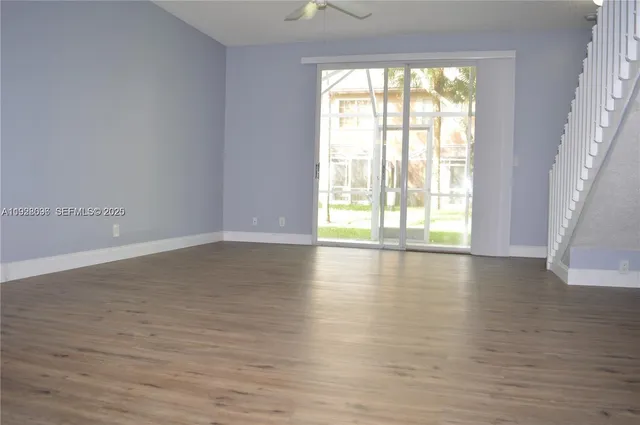 a view of an empty room with wooden floor and a window