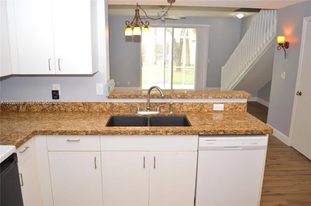 a view of a kitchen with granite countertop a sink and dishwasher with wooden floor