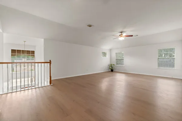 a view of an empty room with a window and wooden floor