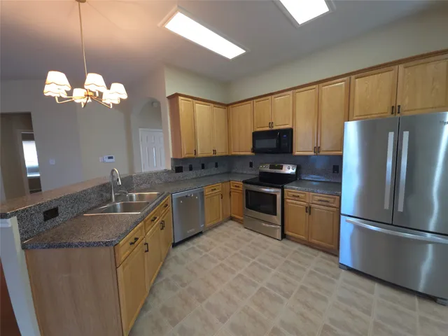a kitchen with granite countertop stainless steel appliances a sink stove and refrigerator