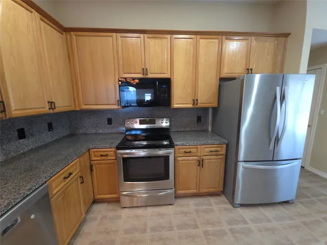 a kitchen with stainless steel appliances granite countertop a refrigerator stove and microwave