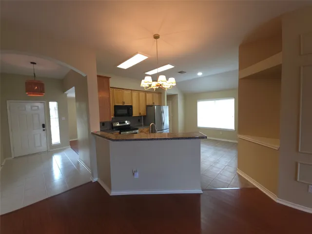 a kitchen with stainless steel appliances granite countertop a refrigerator a sink dishwasher a stove and a dining table with wooden floor