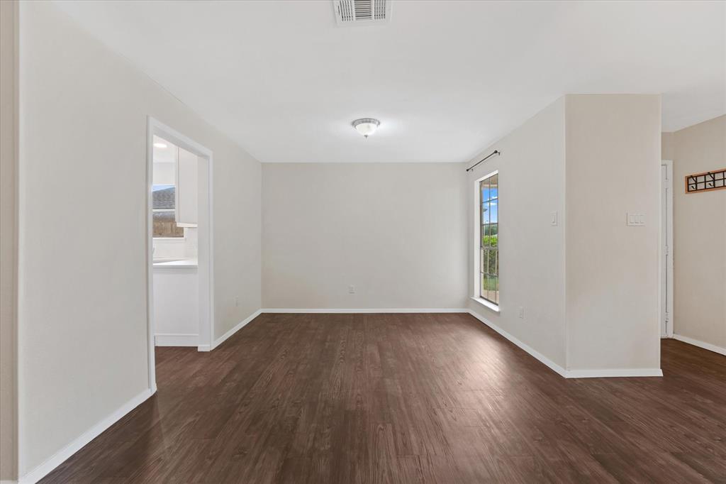 4007 Ridgebrook Drive Arlington, TX 76015 - Photo 6 of 18 Spacious room featuring wood-finish flooring, light-toned walls, a large window, a ceiling-mounted light fixture, and white baseboards