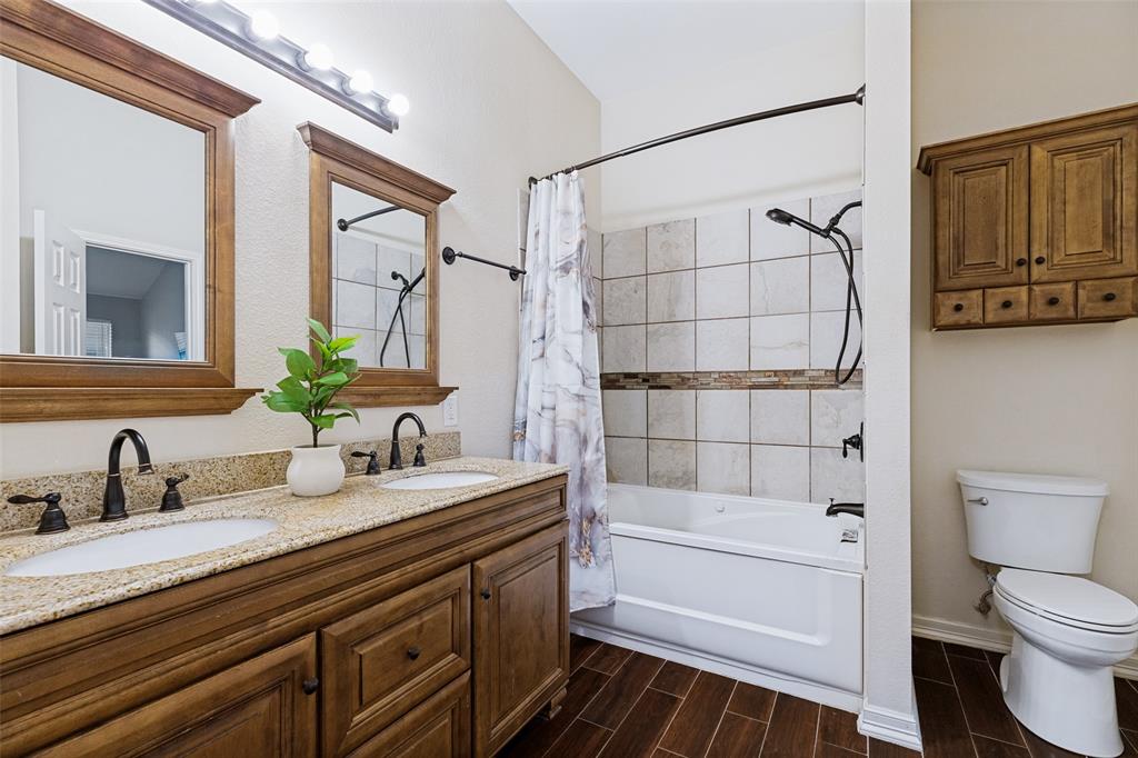 4305 Ridgewood Road Melissa, TX 75454 - Photo 15 of 26 Bathroom featuring a double vanity with granite-style countertops, wood-finish cabinetry, and framed mirrors