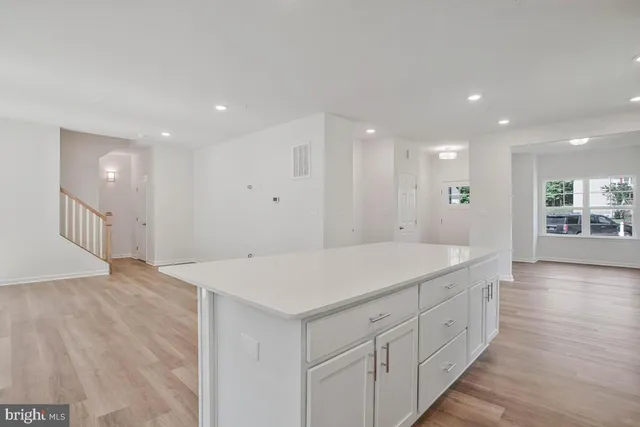 a kitchen with stainless steel appliances a stove a microwave a sink a refrigerator white cabinets and wooden floor