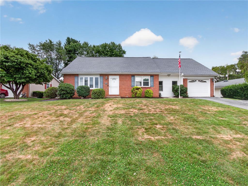A classic ranch home presents with a tidy facade, a manicured front yard, and an attached garage.
