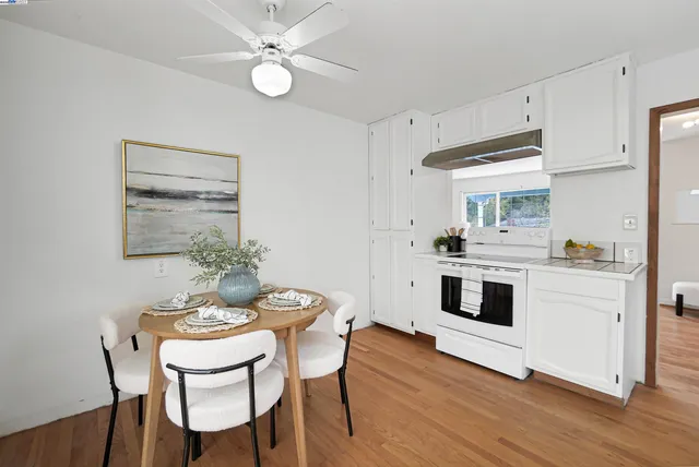a kitchen with white cabinets stove and white stainless steel appliances