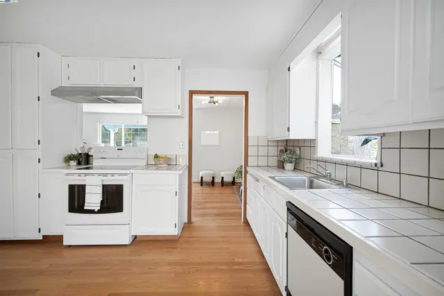 a kitchen with stainless steel appliances white cabinets and wooden floor