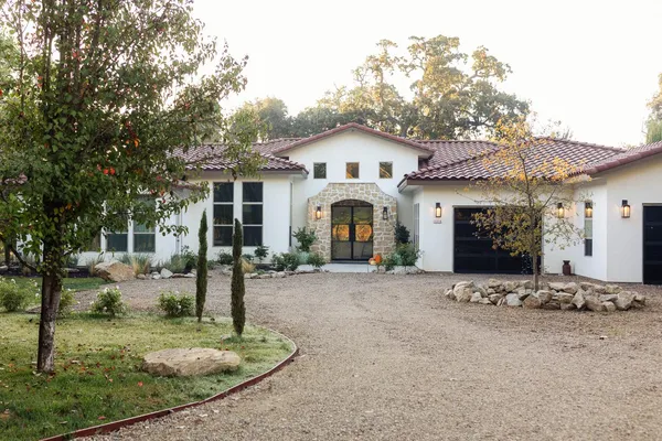 a view of a white house with a small yard and large tree