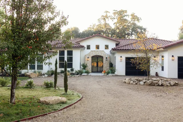 a view of a white house with a small yard and large tree