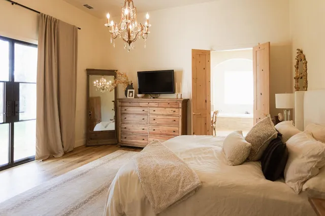a bedroom with a bed a flat screen tv and a chandelier