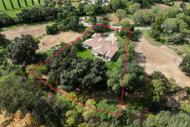 an aerial view of a house with a yard and lake view